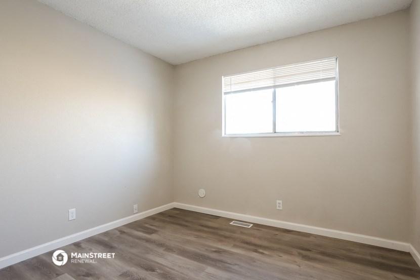 a bedroom with a window and a wooden floor