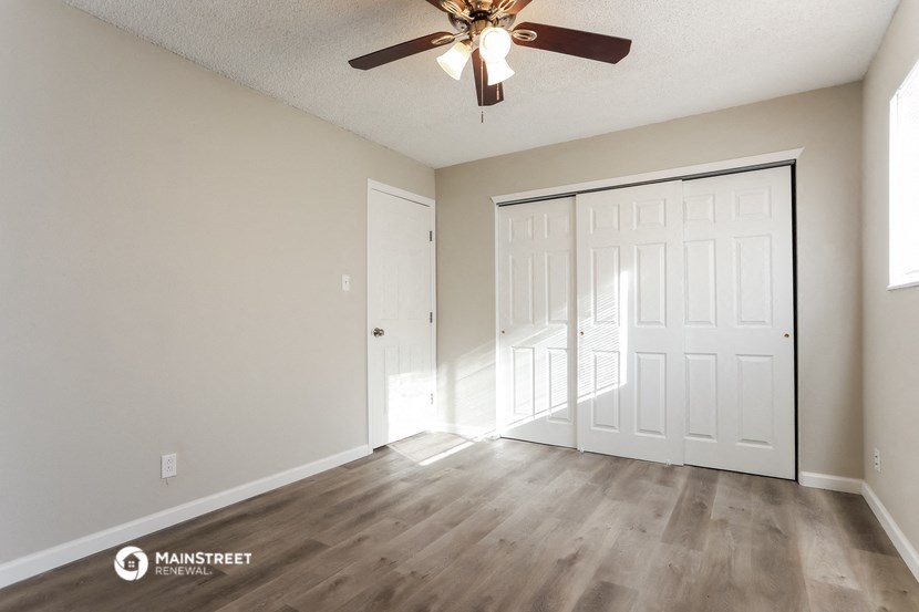 an empty living room with a ceiling fan and a closet