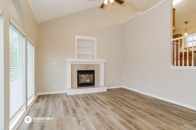 an empty living room with a fireplace and a staircase