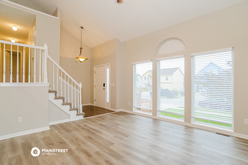 an empty living room with a staircase and large windows