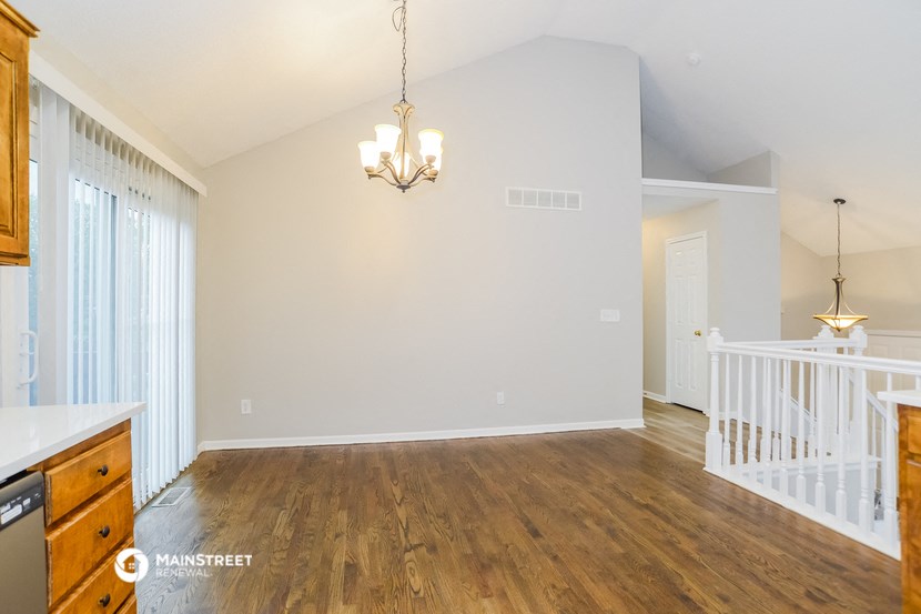 the dining room and living room of a renovated house with a staircase and a window