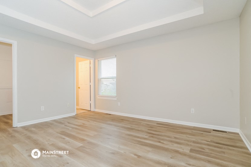 the spacious living room with wood flooring and white walls