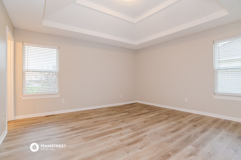the spacious living room with hardwood flooring and two windows