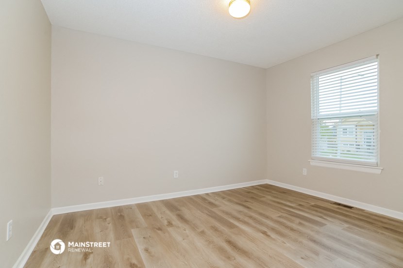 the spacious living room with wood floors and white walls