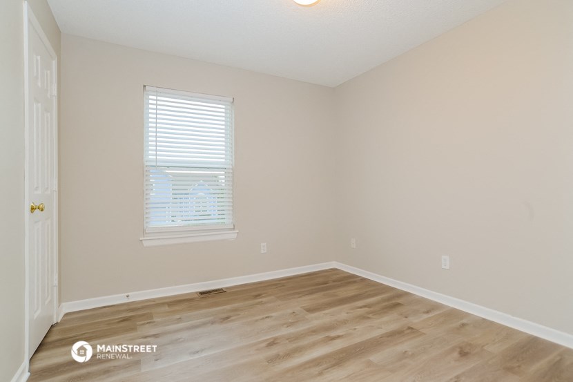 the upstairs bedroom with hardwood flooring and a window