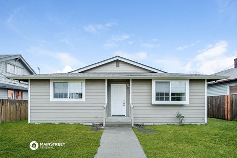 a small gray house with a white door and a sidewalk