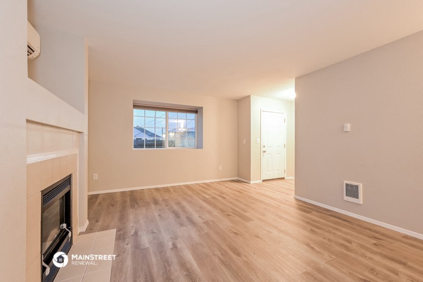 an empty living room with a fireplace and wood flooring