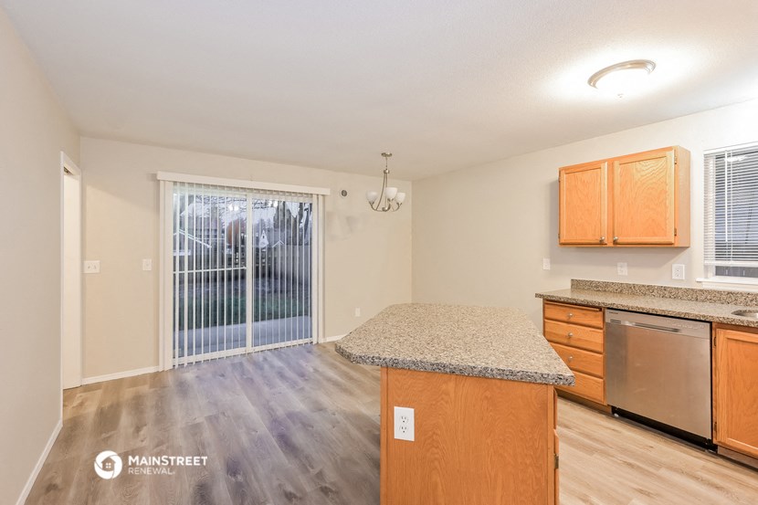 the kitchen and living room of an open floor plan with a door to the backyard