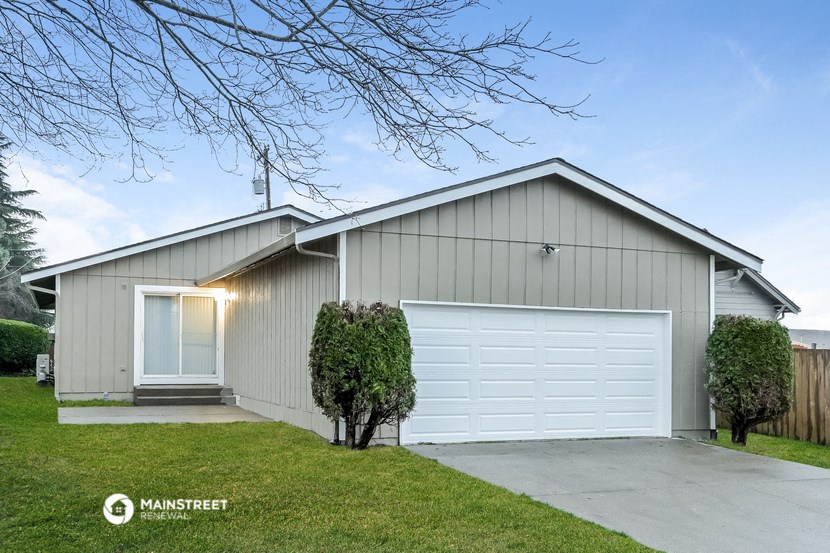 a white house with a white garage door and a lawn