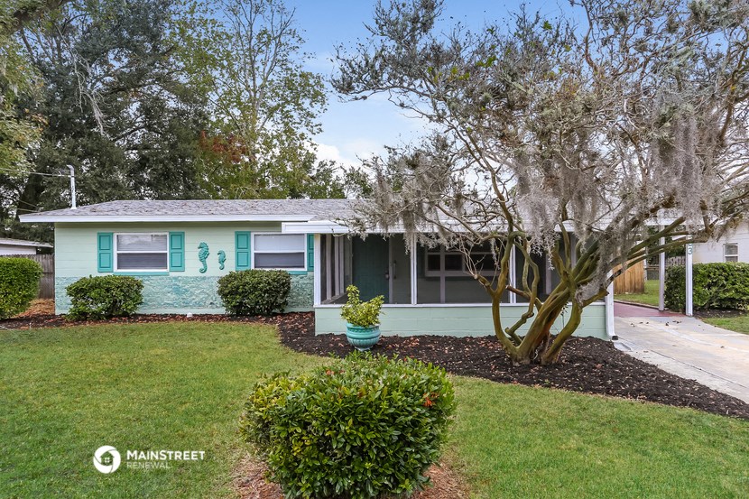 a light blue house with a yard and trees