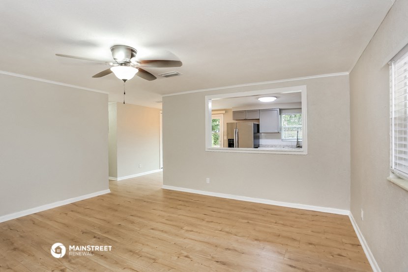 an empty living room with a ceiling fan and a window
