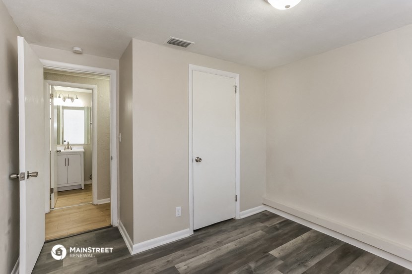 the living room of an apartment with white walls and wood flooring