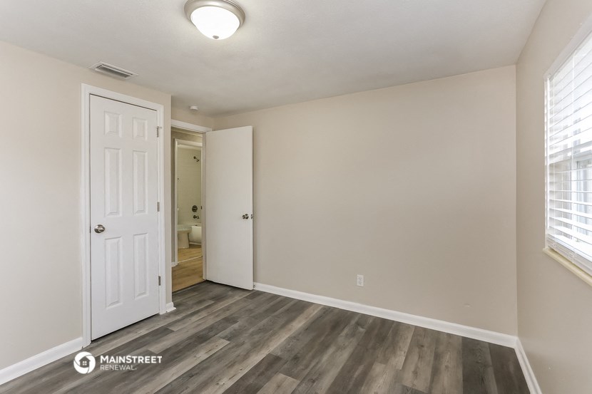the spacious living room with wood flooring and a white door