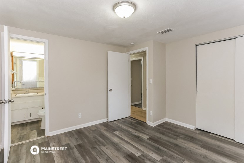 the living room of an apartment with white walls and wood flooring