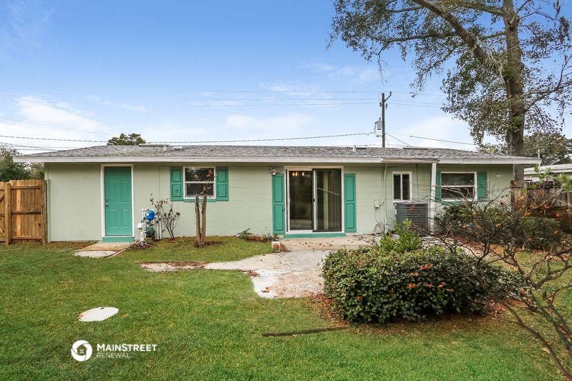 a small green house with green doors and a yard