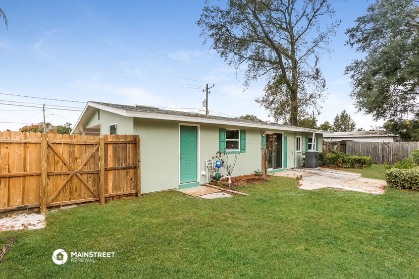a small green house with a yard and a wooden fence