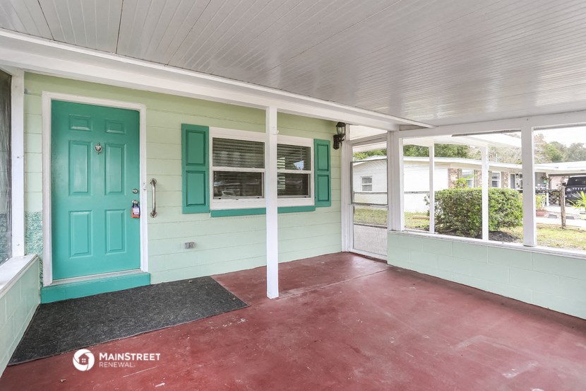 the front porch of a house with a blue door and green shutters