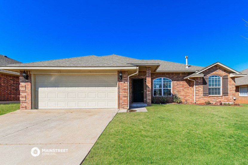a brick house with a garage door and a lawn