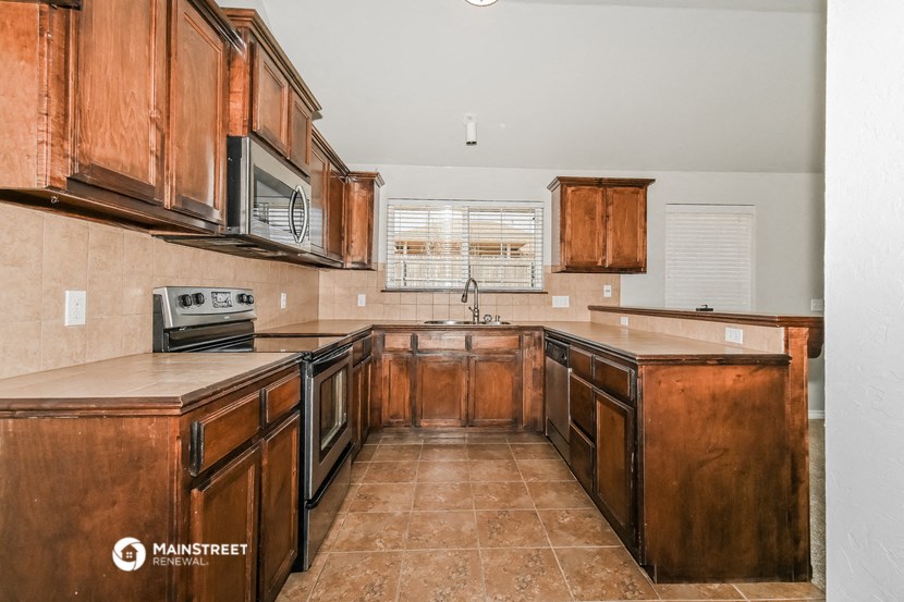 a kitchen with wooden cabinets and appliances and tile floors