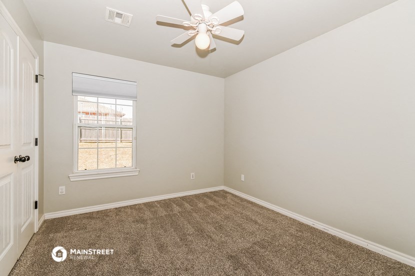 the bedroom has carpet and a ceiling fan
