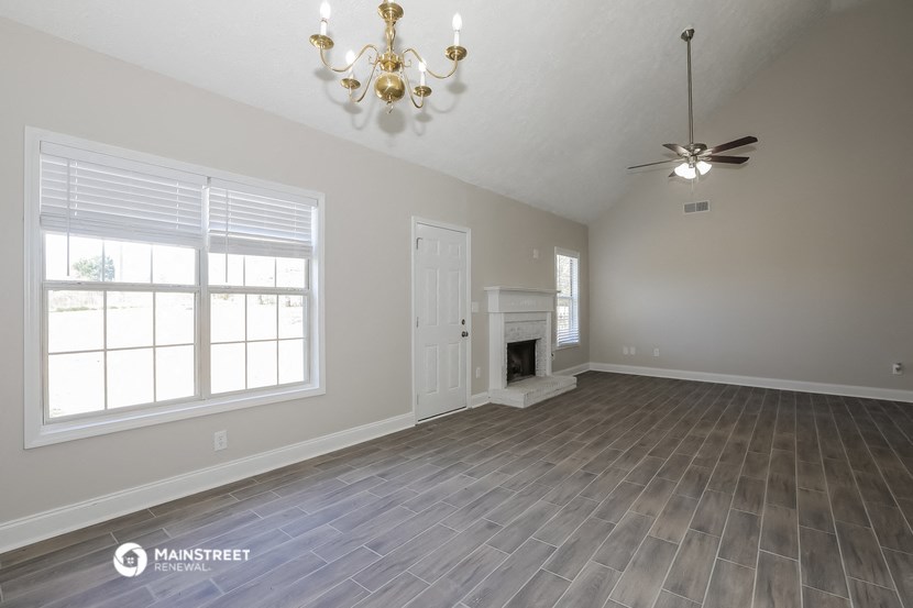 the living room of an empty house with a fireplace and a ceiling fan