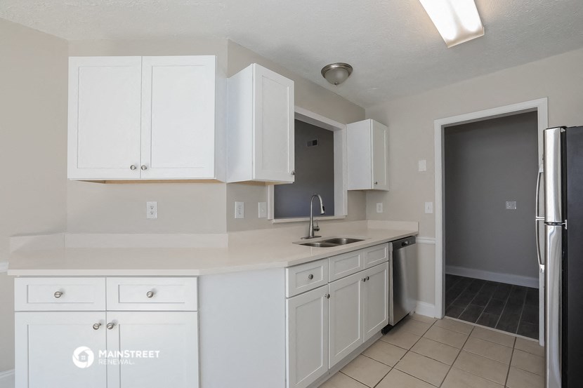 an empty kitchen with white cabinets and a stainless steel refrigerator