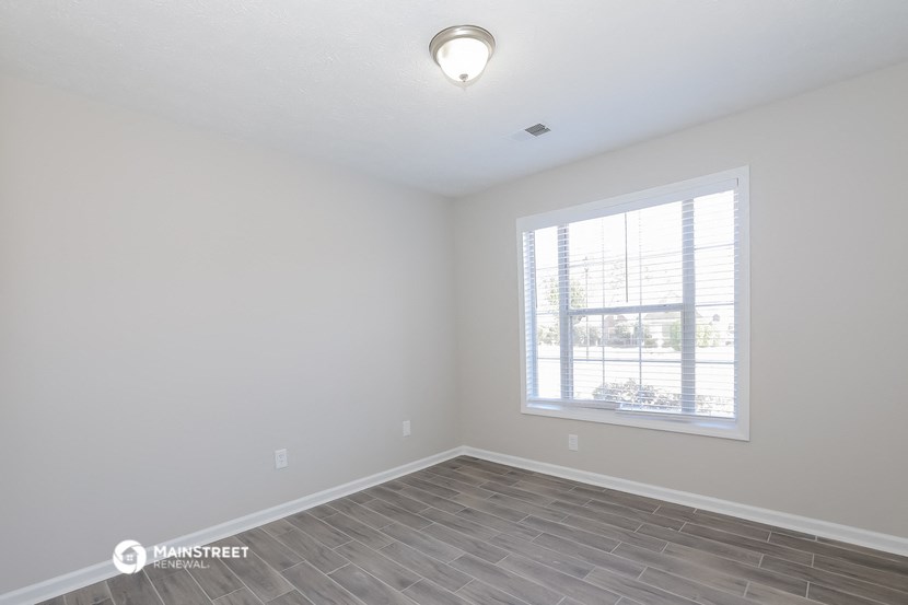 the spacious living room with a large window and wood flooring