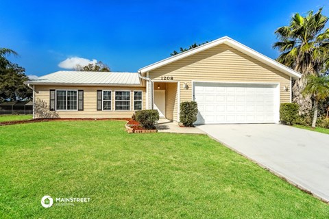 a yellow house with a white garage door and a lawn