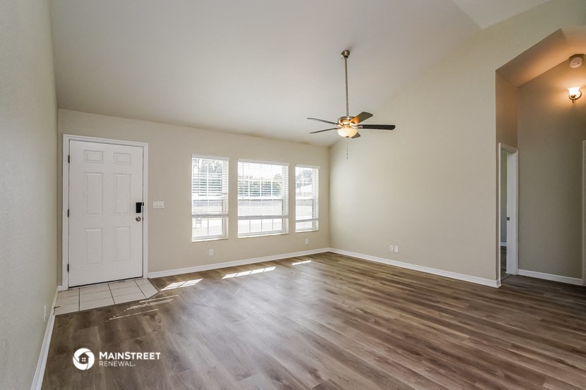 the living room of an empty house with a ceiling fan