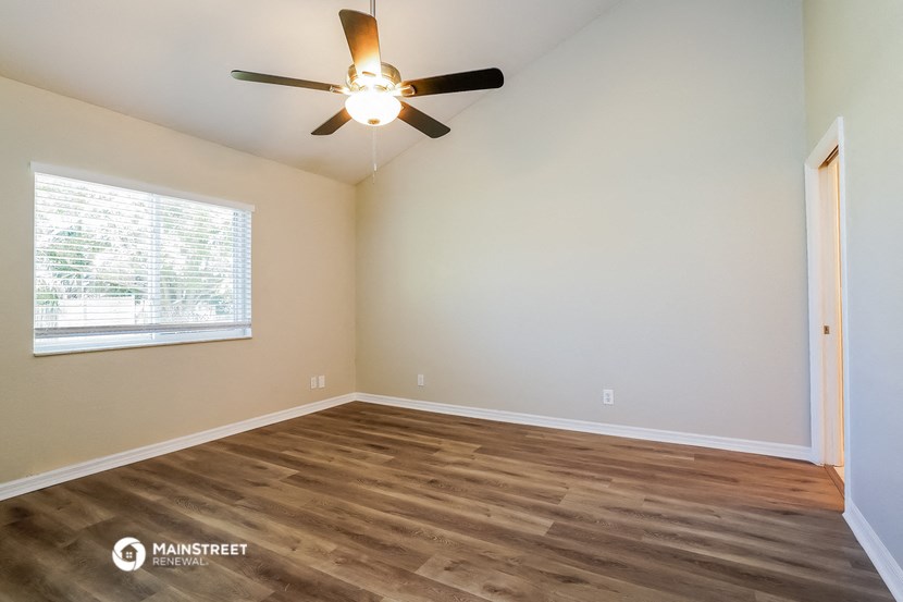 the spacious living room with hardwood floors and a ceiling fan