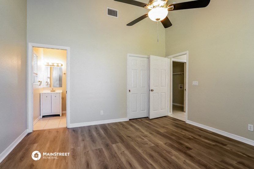 an empty living room with a ceiling fan and a door to a bathroom