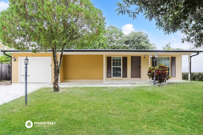 the front of a yellow house with a lawn and a tree
