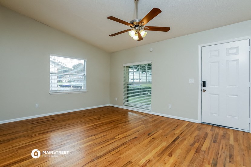 the spacious living room with hardwood floors and a ceiling fan