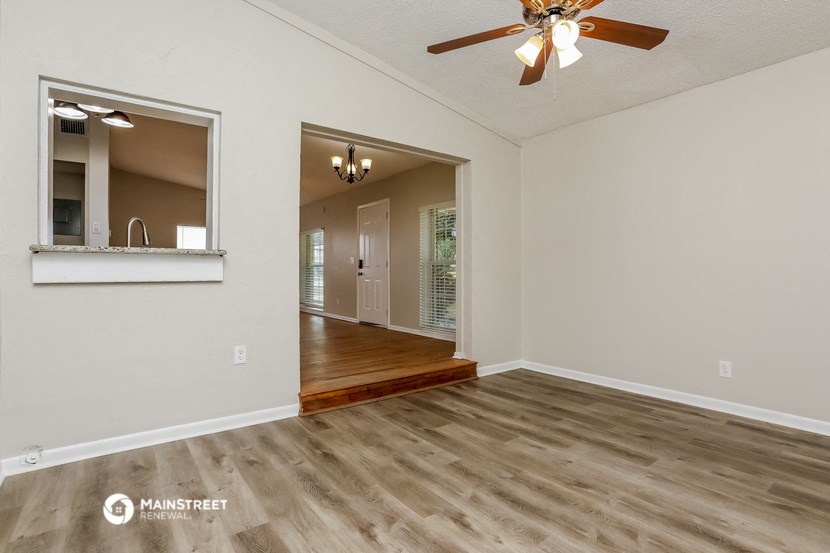the spacious living room and dining room with a ceiling fan