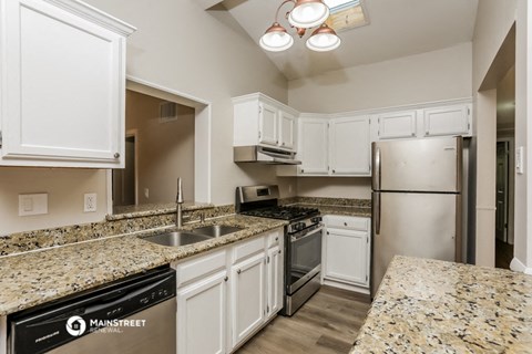 a kitchen with granite counter tops and white cabinets