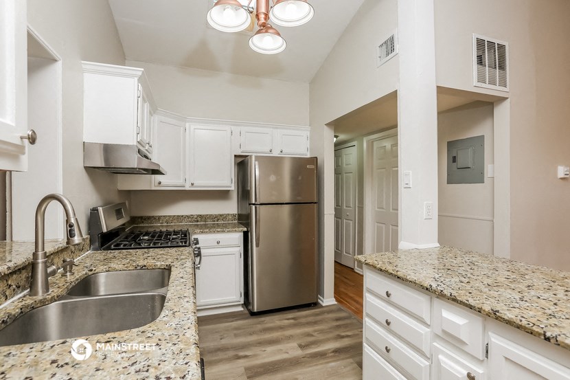 a kitchen with granite counter tops and a stainless steel refrigerator