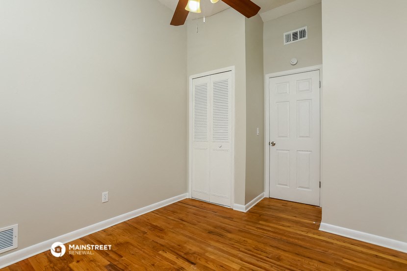 a bedroom with wood flooring and a white door