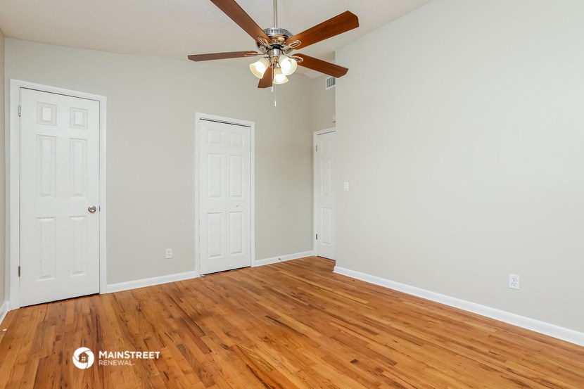 a bedroom with a ceiling fan and wood floors