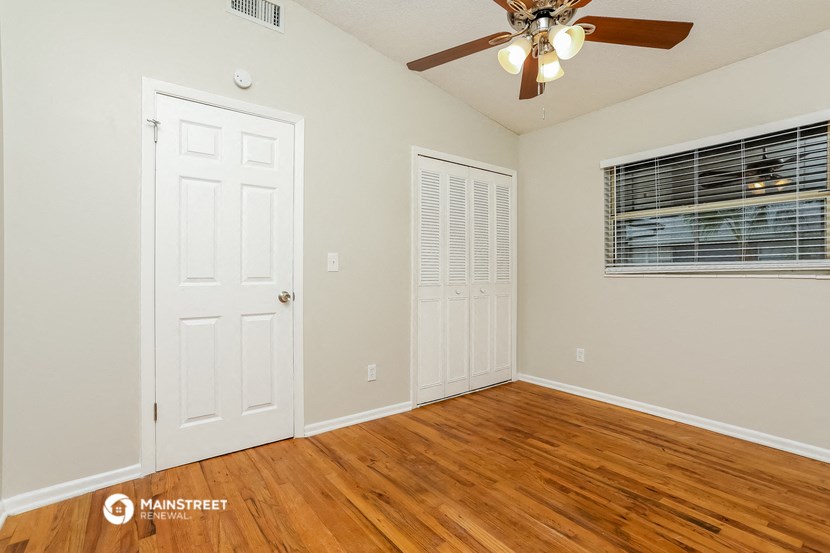 the living room of a home with wood flooring and a ceiling fan