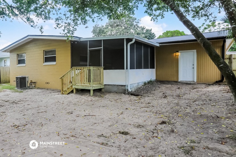a small yellow house with a porch and a white door