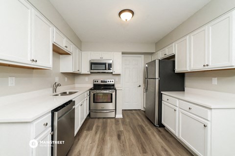 a white kitchen with stainless steel appliances and white cabinets