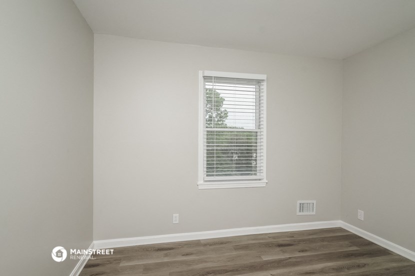 a room with white walls and a window with blinds