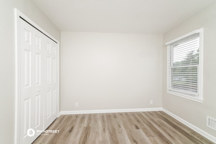 an empty room with white walls and wood floors