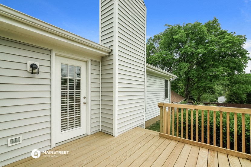 a backyard deck with a fence and a white house