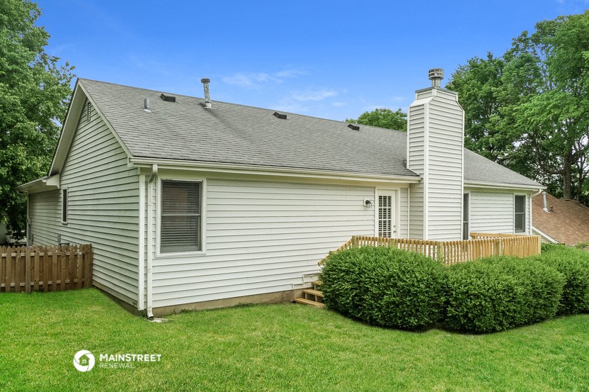 a small white house with a yard and a wooden fence