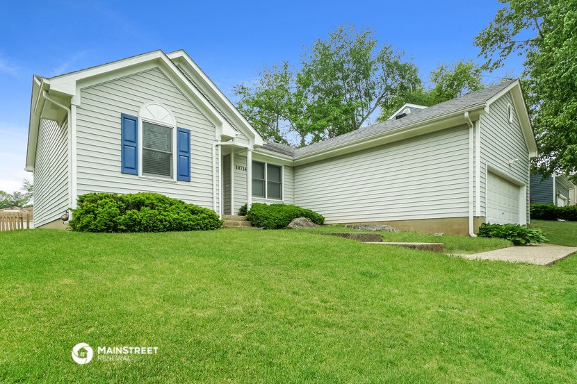 a white house with blue shutters on the side of a green lawn