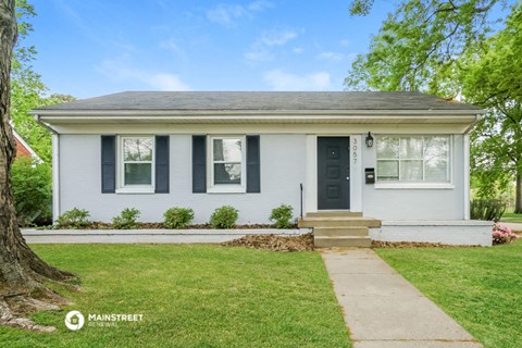 a white house with black shutters and a sidewalk in front of it