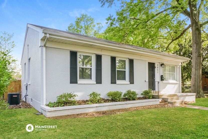 a small white house with black shutters and a lawn