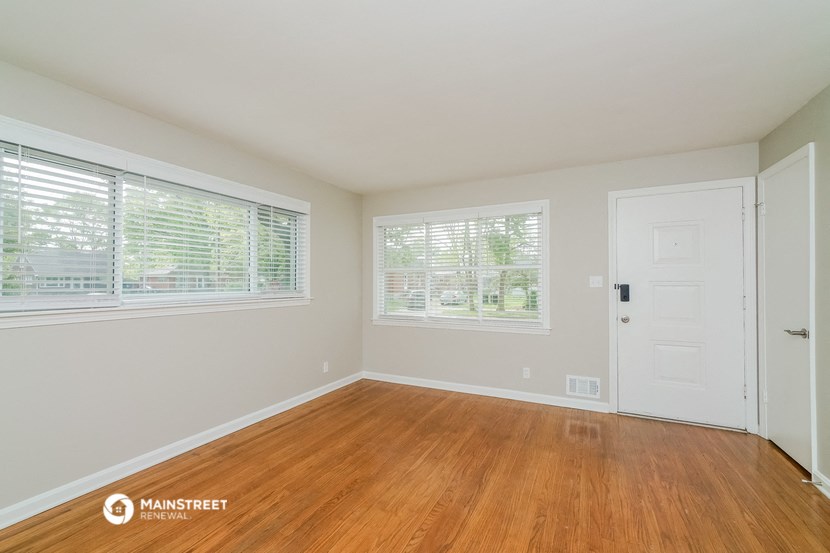 the living room of a home with wood floors and a white door and window