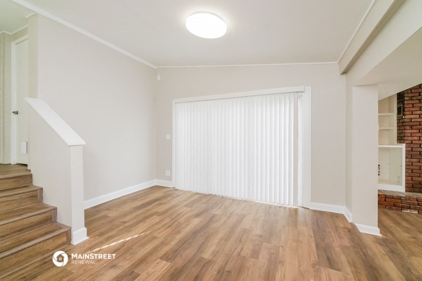 a living room with white walls and wood flooring and a sliding glass door